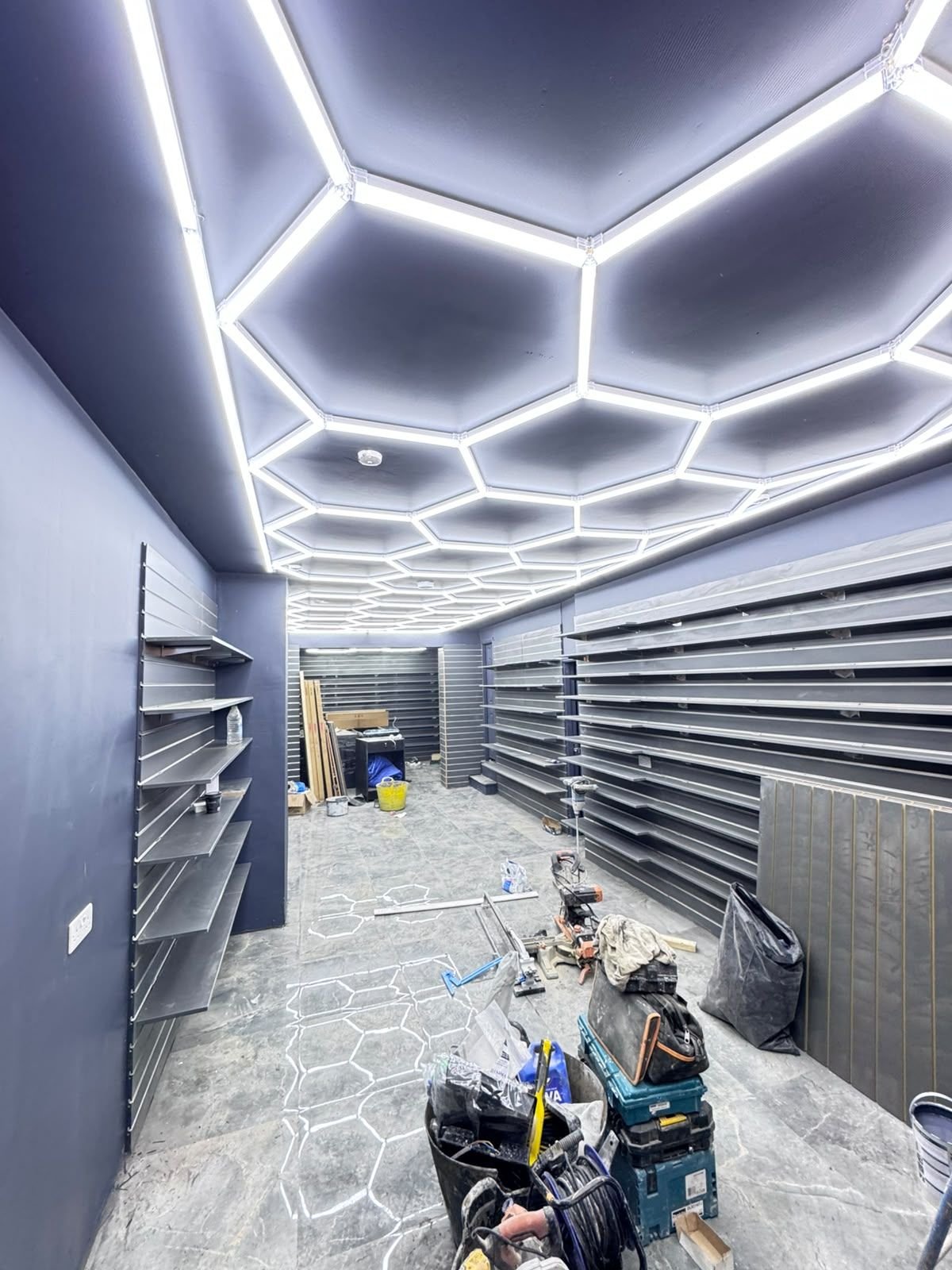 Retail unit with hexagon LED ceiling lighting, wall shelving and tiled floor