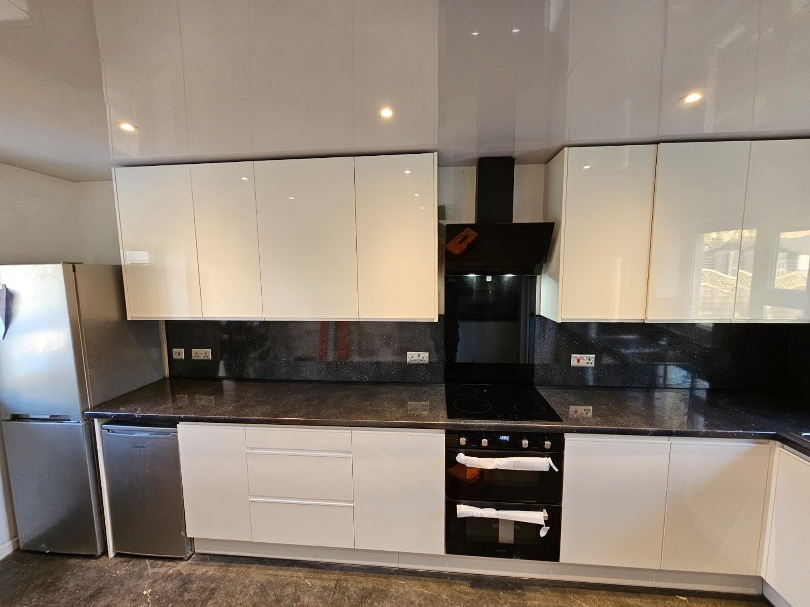 Cream gloss kitchen with black sparkle worktop, splashback and built-in double oven