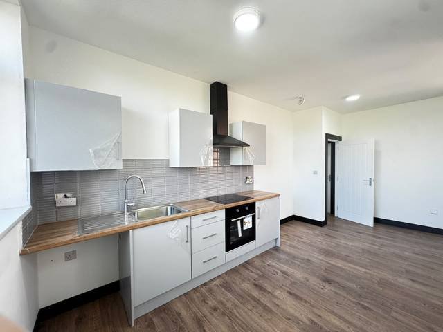 Open-plan kitchen with grey units, oak-effect worktop and new wood-effect flooring
